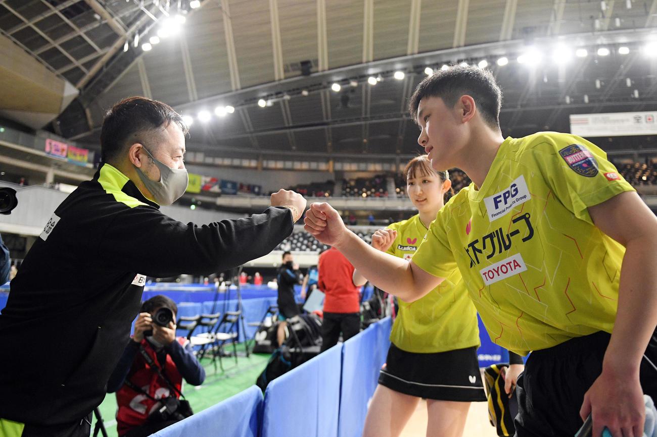 混合ダブルス3回戦を勝利した張本智（右）と早田（中央）はベンチのアドバイザーとタッチを交わす（撮影・滝沢徹郎）