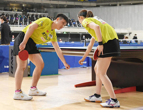 混合ダブルス準々決勝で台の下で作戦を確認する張本（左）と早田（撮影・滝沢徹郎）