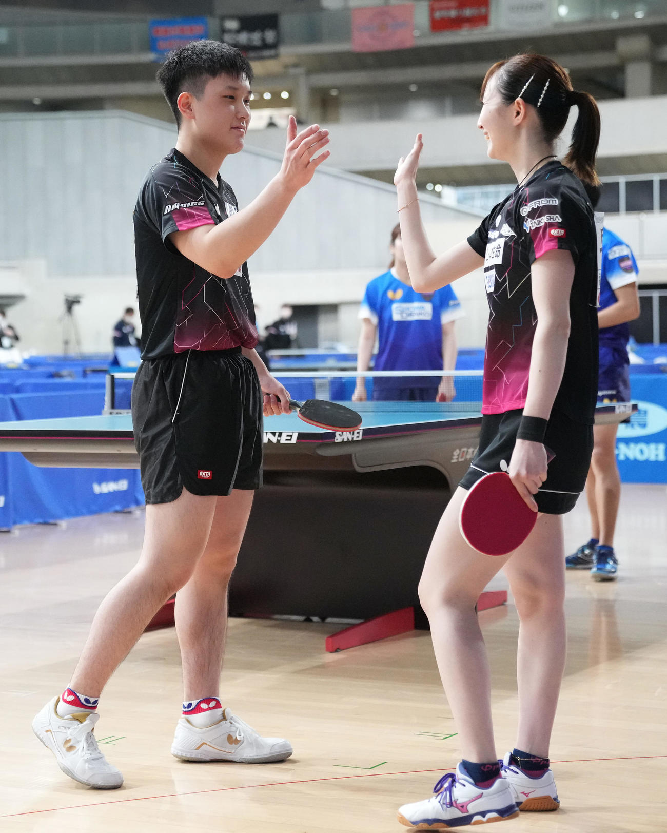 混合ダブルスで優勝しタッチを交わす張本（左）、早田組（撮影・鈴木みどり）