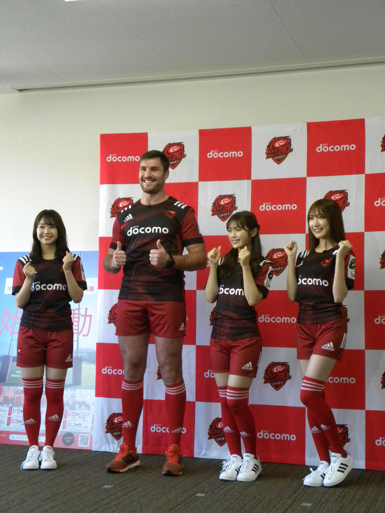 NTTドコモレッドハリケーンズ大阪の公式アンバサダーに就任したNMB48の加藤夕夏（左）、渋谷凪咲（右から2人目）、原かれん（右）はエラスマス主将とポーズを決める＝2021年10月14日