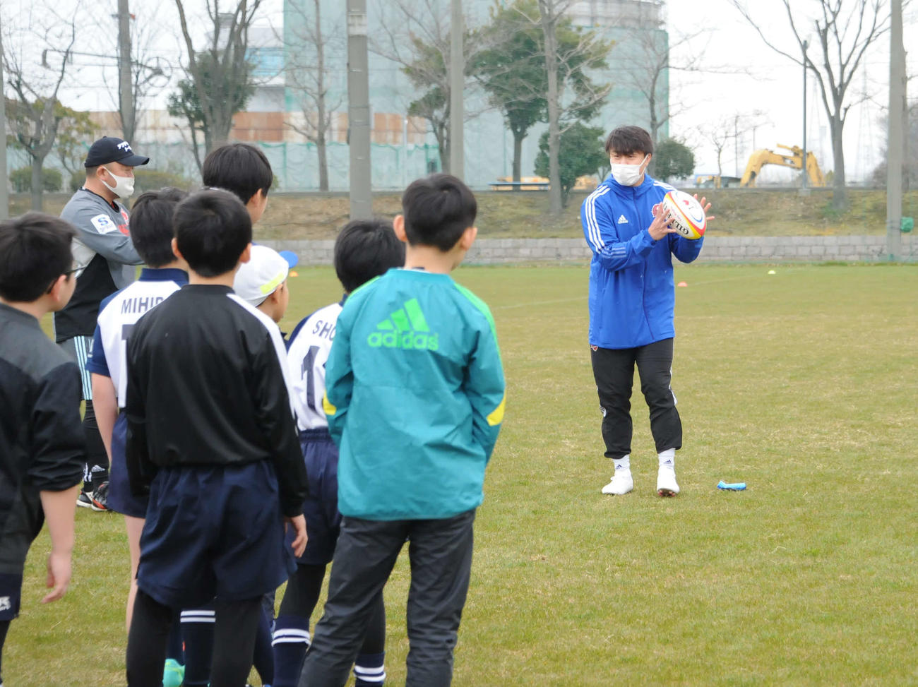 小学生にパスを指導するリーグワン大阪の射場大輔（右）