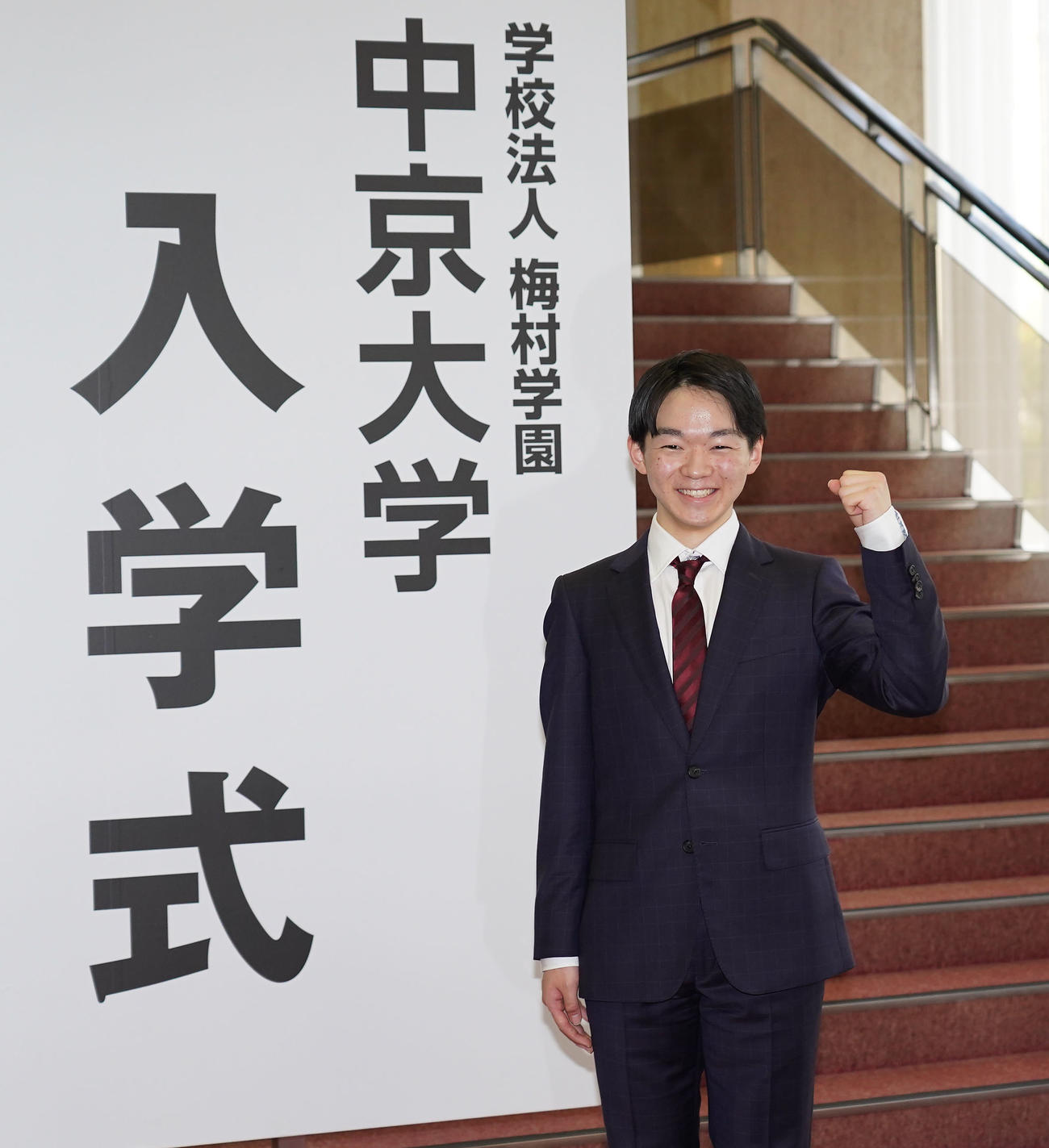 中京大学入学式ボードの前で報道陣の要望に応え笑顔でポーズをとる鍵山（撮影・森本幸一）