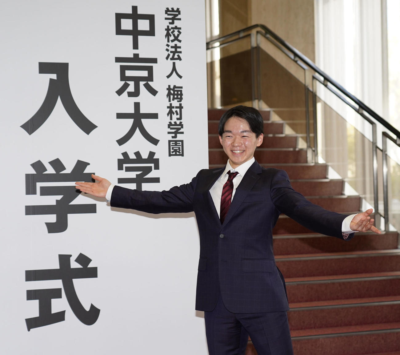 中京大学入学式ボードの前で報道陣の要望に応え笑顔でポーズをとる鍵山（撮影・森本幸一）
