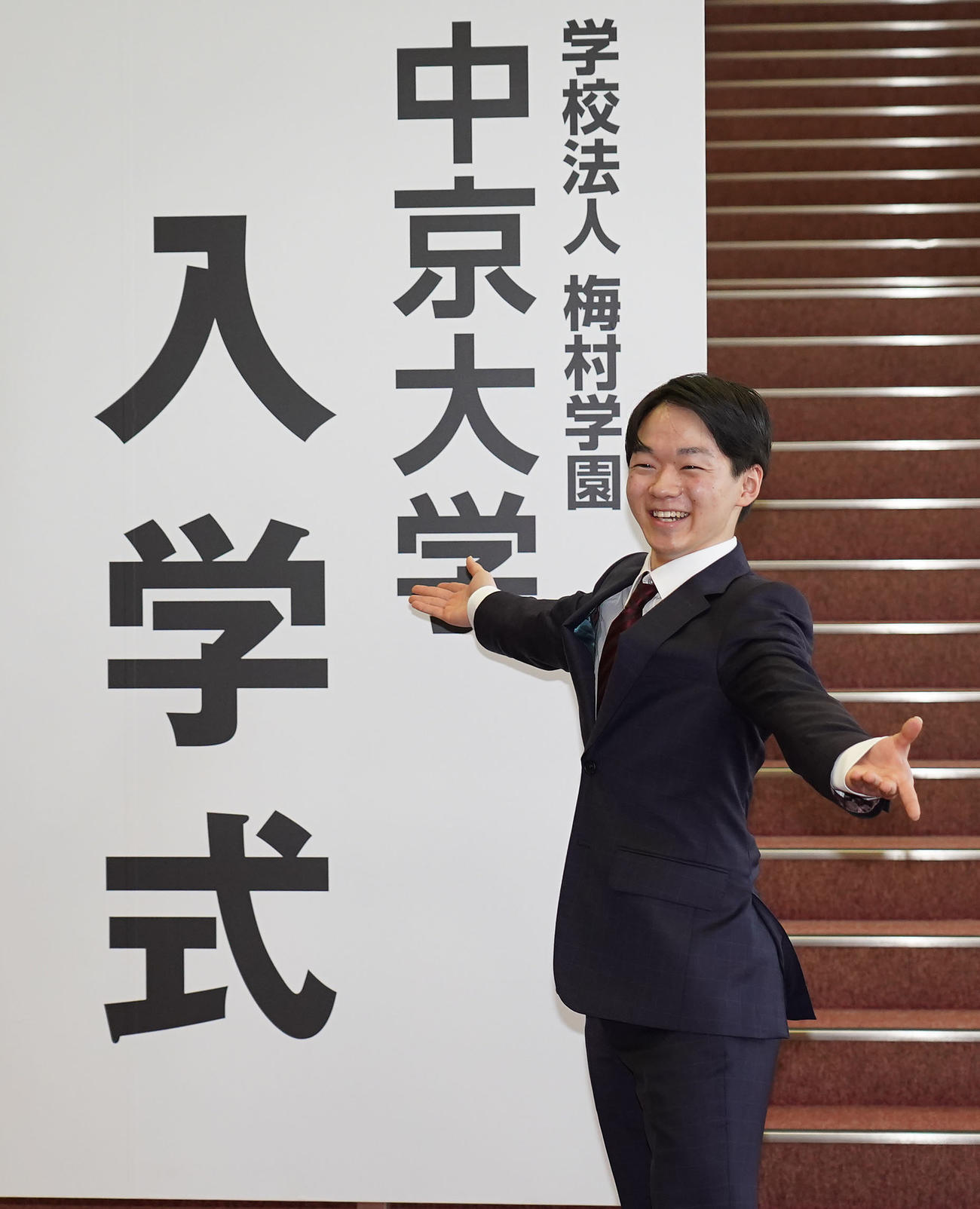 中京大学入学式ボードの前で報道陣の要望に応え笑顔でポーズをとる鍵山（撮影・森本幸一）