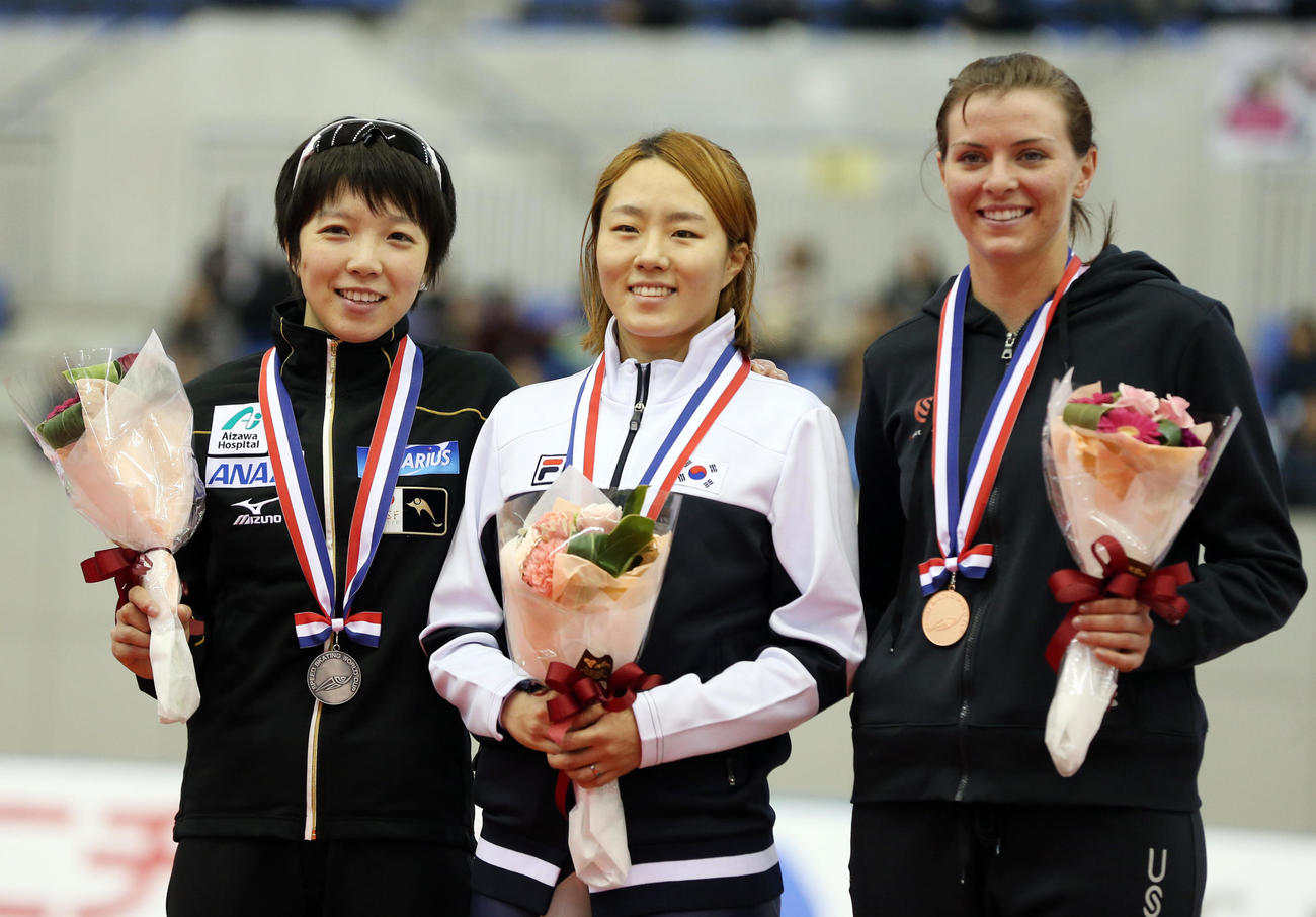 12年12月、女子500メートルディビジョンAで2位に入った小平（左）は、表彰式で笑顔を見せる。中央は1位の李相花、右は3位のリチャードソン