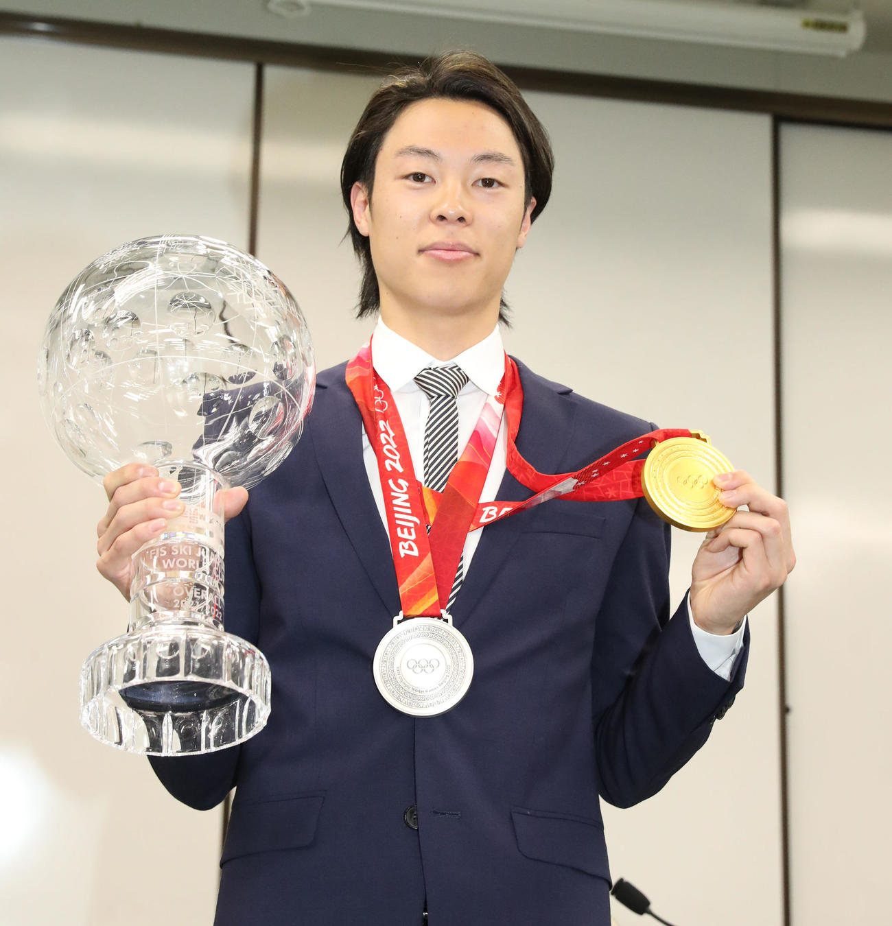土屋ホームスキー部2021－2022シーズン報告会でW杯個人総合優勝のトロフィーと北京五輪で獲得したメダルを披露する小林（撮影・佐藤翔太）