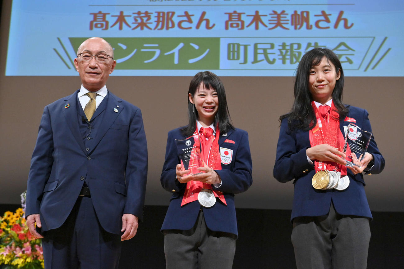 オンライン町民報告会に出席し特別町民栄誉賞の表彰を受け、飯田幕別町長（左）との記念撮影で笑顔を見せるスピードスケートの高木菜那（中央）と美帆姉妹（代表撮影）