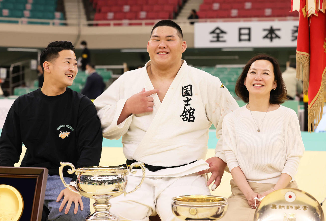 家族での記念撮影に笑顔を見せる斉藤（中央）。左は兄一郎さん、右は母三恵子さん（撮影・足立雅史）