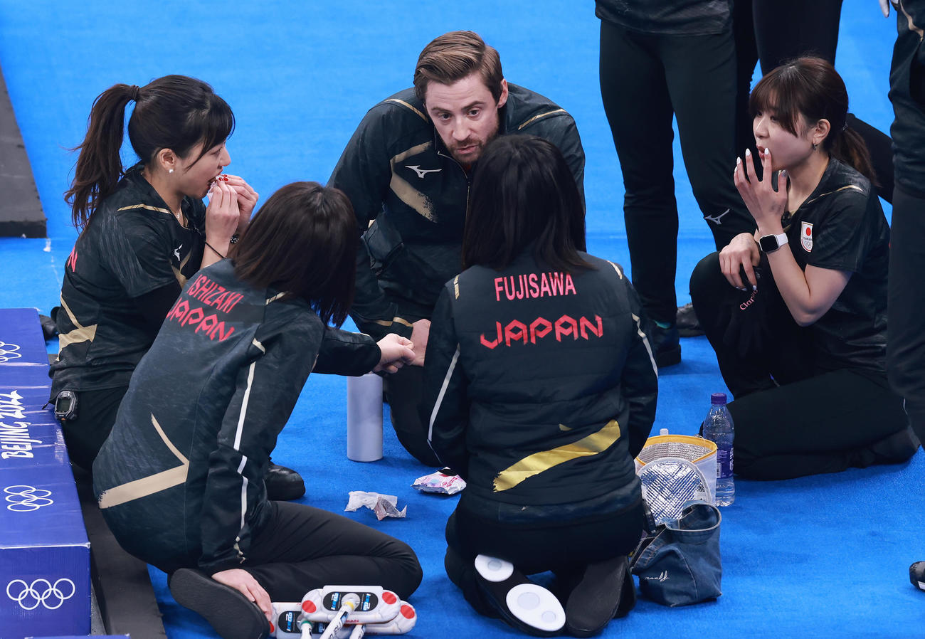日本対スイス　第5エンドを終え、軽食をとりながらリンドコーチ（中央）の話しを聞くロコ・ソラーレの選手たち（2022年2月13日撮影）