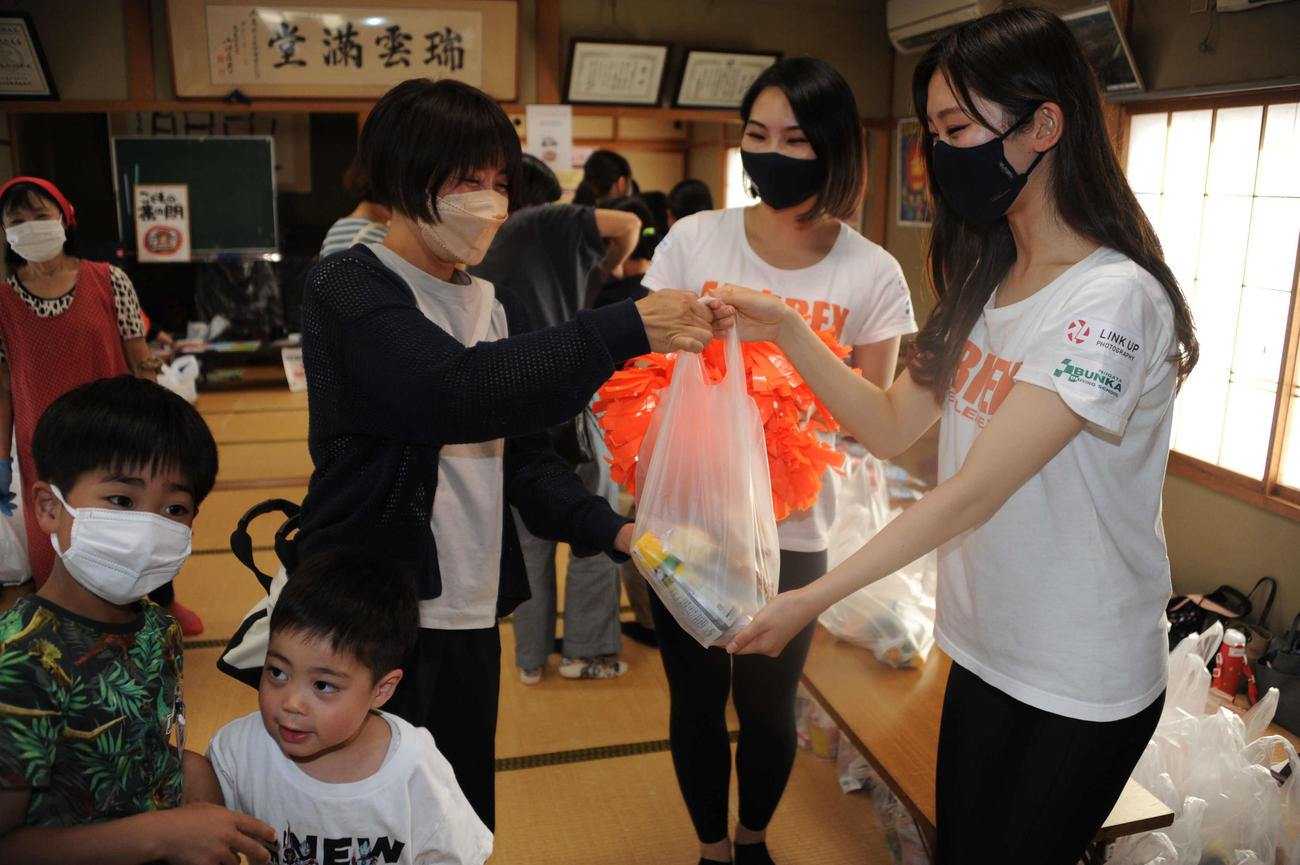 来訪者に食品の詰め合わせを手渡すアルビレックスチアリーダーズの結城（右）と金子（右から2人目）