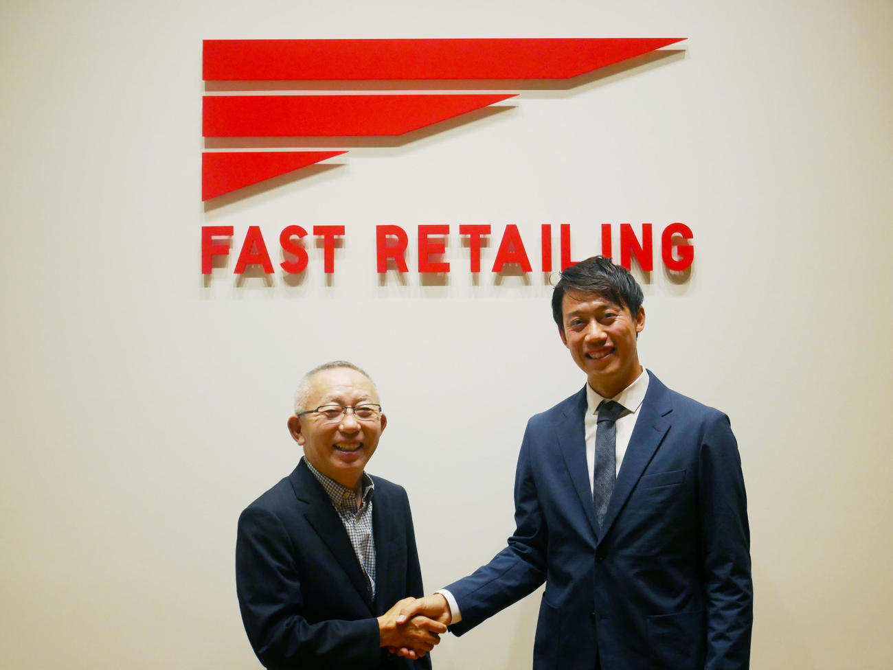 ユニクロと所属契約を結びファーストリテイリングの柳井正社長（左）と握手する錦織