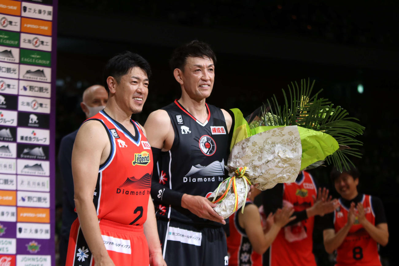 チームレジェンド対チームナイン　レバンガ北海道佐古監督（左）から花束を受け取る折茂氏（撮影・山崎純一）
