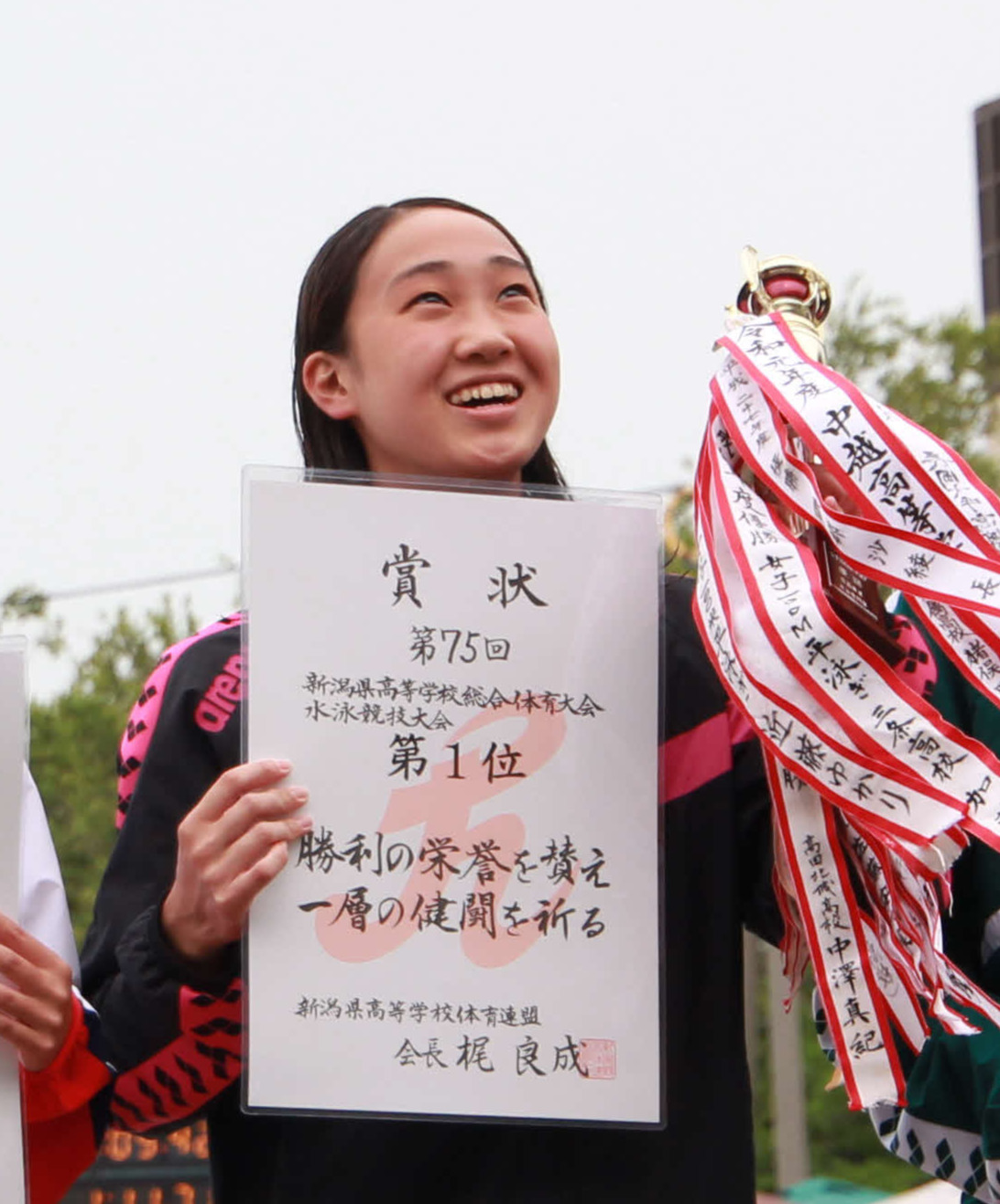表彰台で笑顔の100メートル平泳ぎで優勝の小山