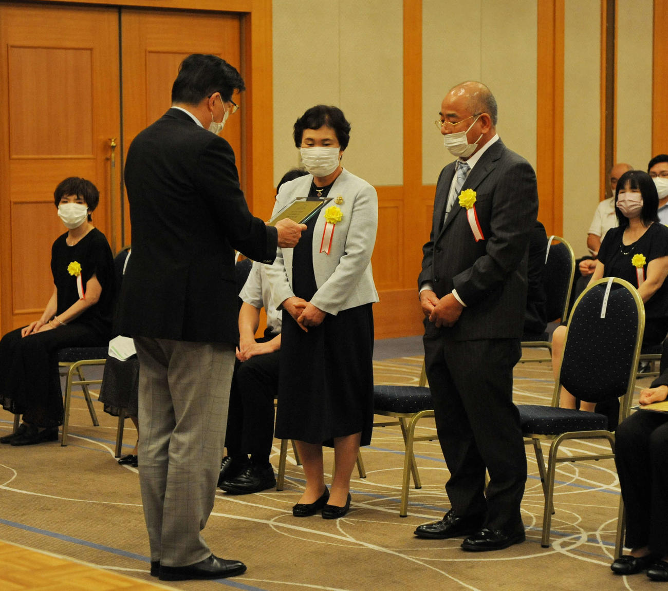 特別優秀選手章の伊藤の代理を務めた、祖父の伊藤健一さん（右）と祖母の町子さん（中央）。左は川勝県知事　