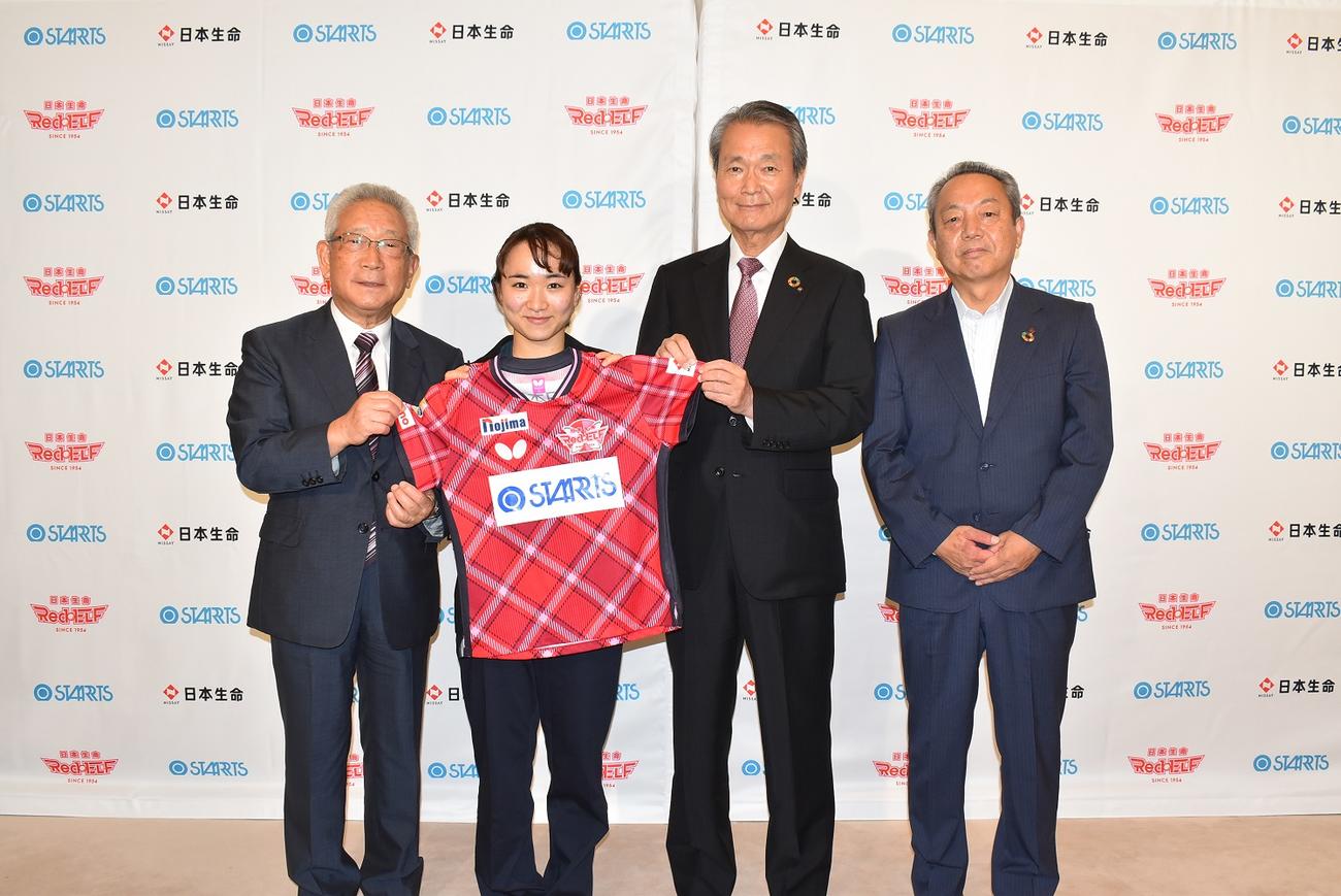 Tリーグの日本生命のユニホームを手に笑顔を見せる伊藤（左から2人目）（スターツ提供）