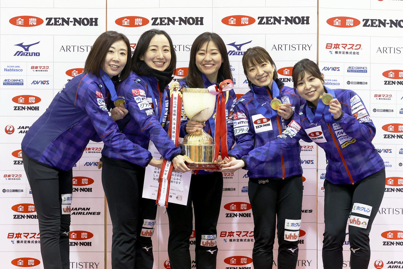 カーリング全農日本選手権で優勝し、表彰台でトロフィーを掲げるロコ・ソラーレの、左から石崎琴美、藤沢五月、吉田知那美、鈴木夕湖、吉田夕梨花（2022年5月29日撮影）