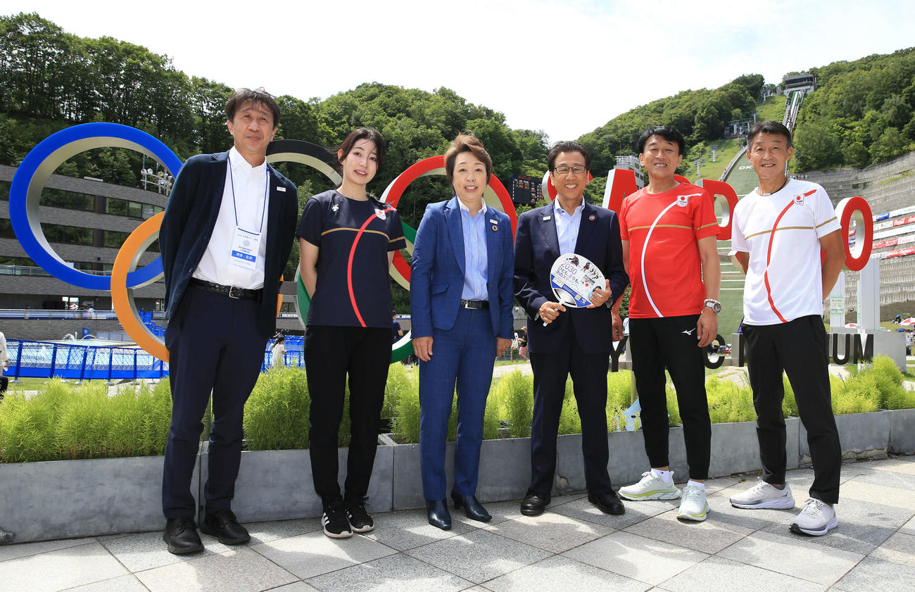 大倉山ジャンプ競技場を背に笑顔で撮影に応じる東京五輪・パラリンピック組織委員会元会長橋本参院議員（左から3人目）と秋元札幌市長（撮影・佐藤翔太）