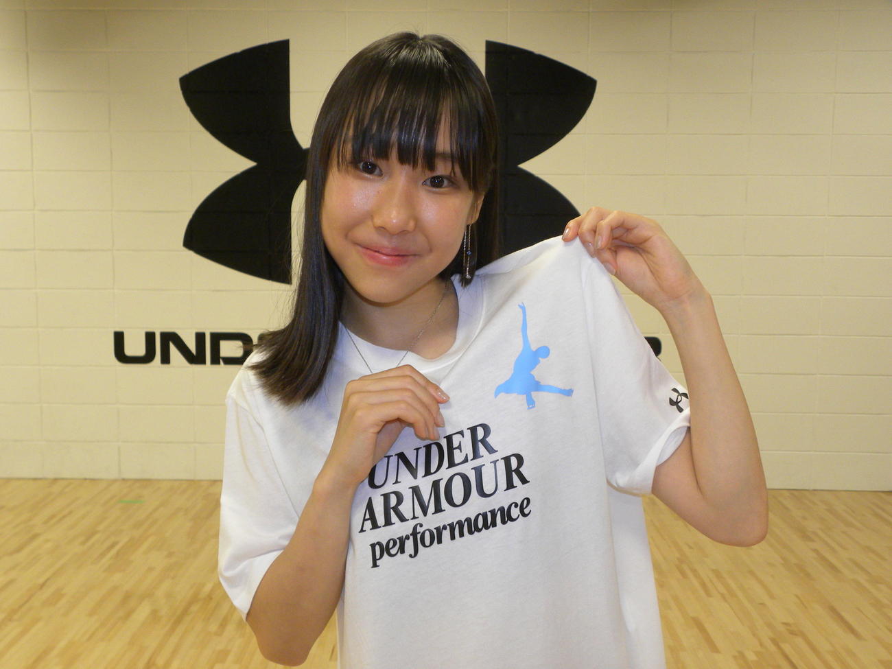 自らのスピンのシルエットが印刷されたアンダーアーマーのTシャツを着用し、笑顔を見せる三原舞依（撮影・松本航）