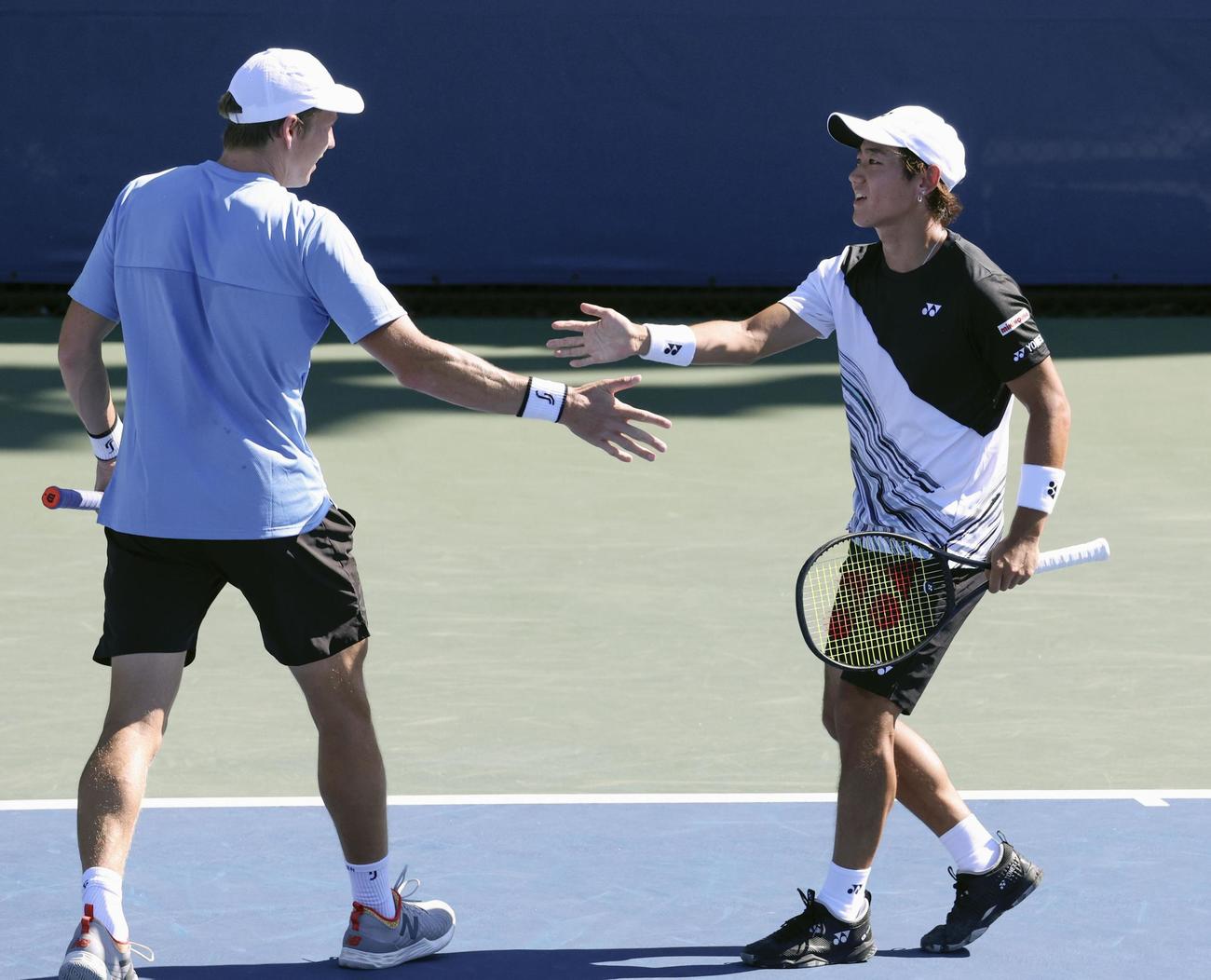 男子ダブルス1回戦でポイントを奪いタッチする西岡良仁（右）、アンドレ・ヨランソン組（共同）