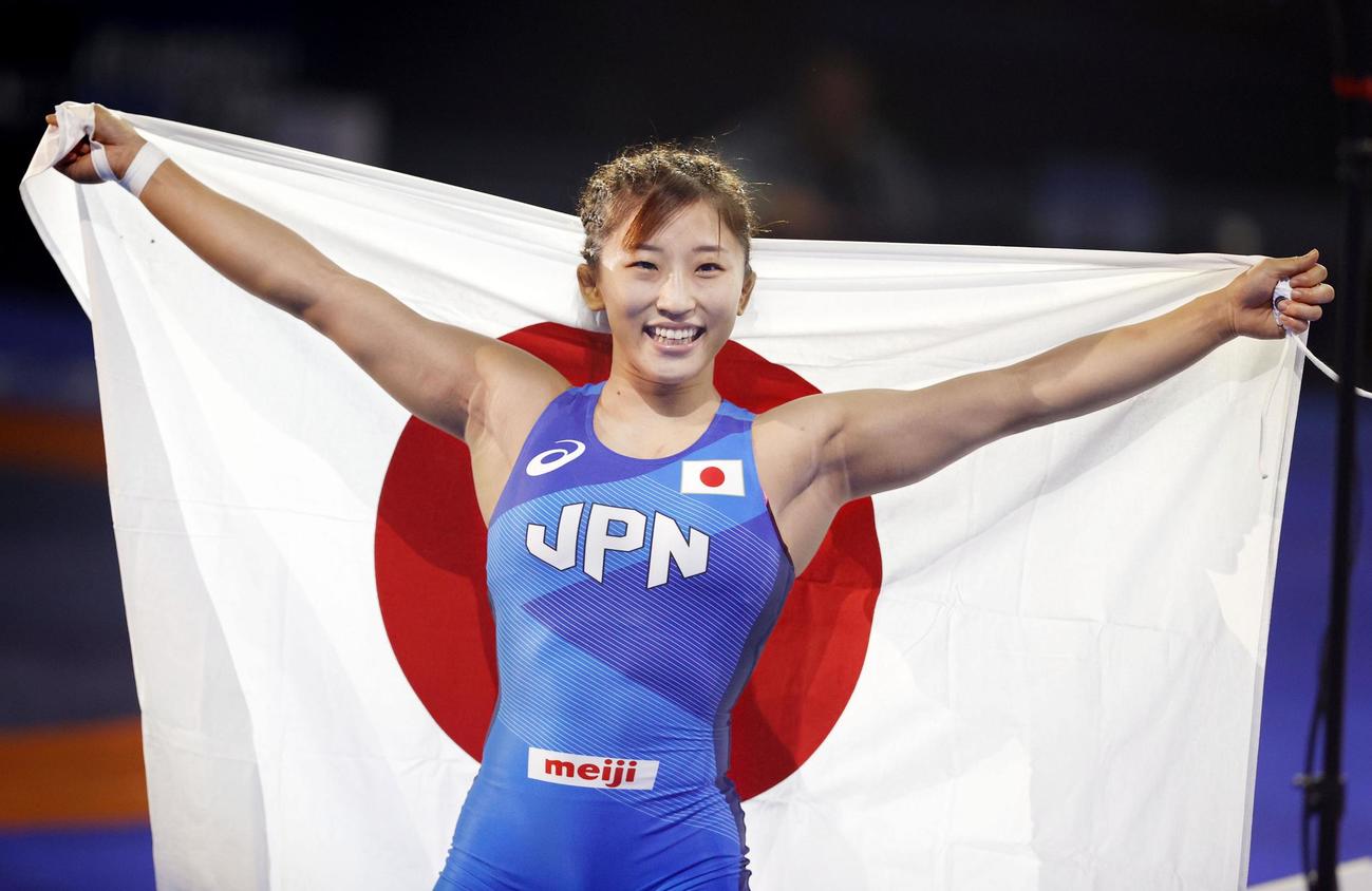 女子50キロ級で優勝し、日の丸を掲げ笑顔の須崎優衣（共同）