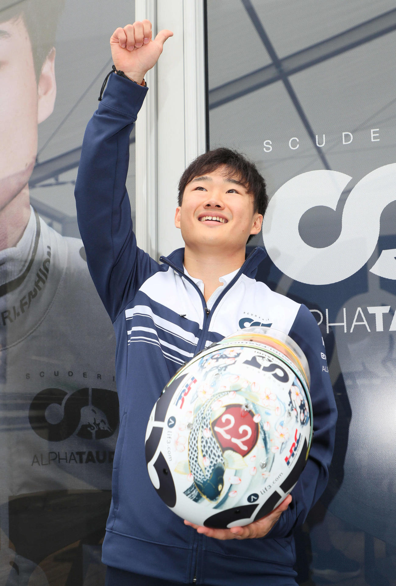 日本GPスペシャルペイントのヘルメットを手に声援に応える角田裕毅（撮影・宮崎幸一）