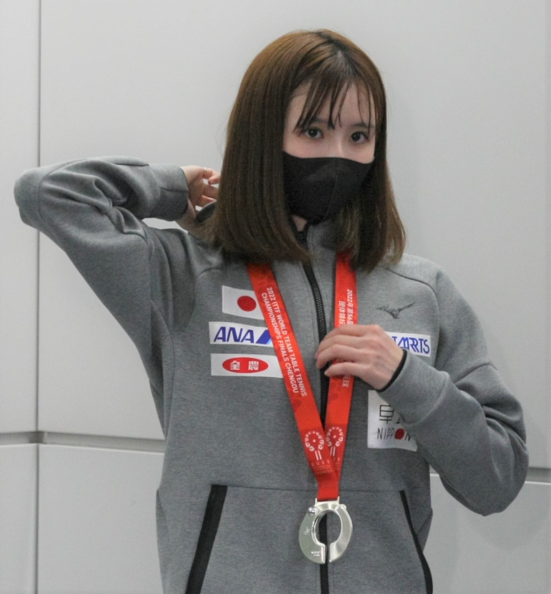 卓球の世界選手権女子団体で銀メダルを獲得し、帰国した成田空港でメダルを首から下げる早田（撮影・藤塚大輔）