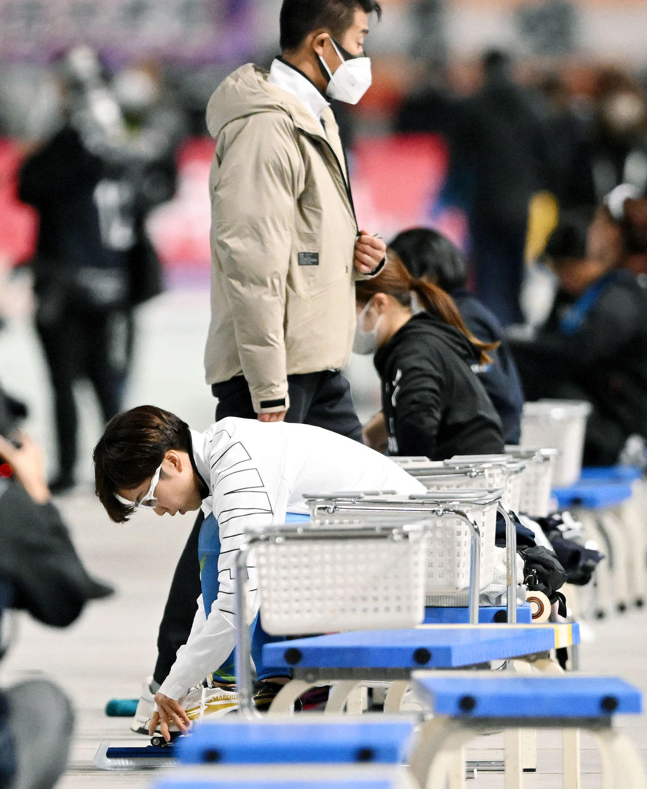 引退レースを終えスケート靴を脱ぐ小平。奥は結城コーチ（撮影・滝沢徹郎）