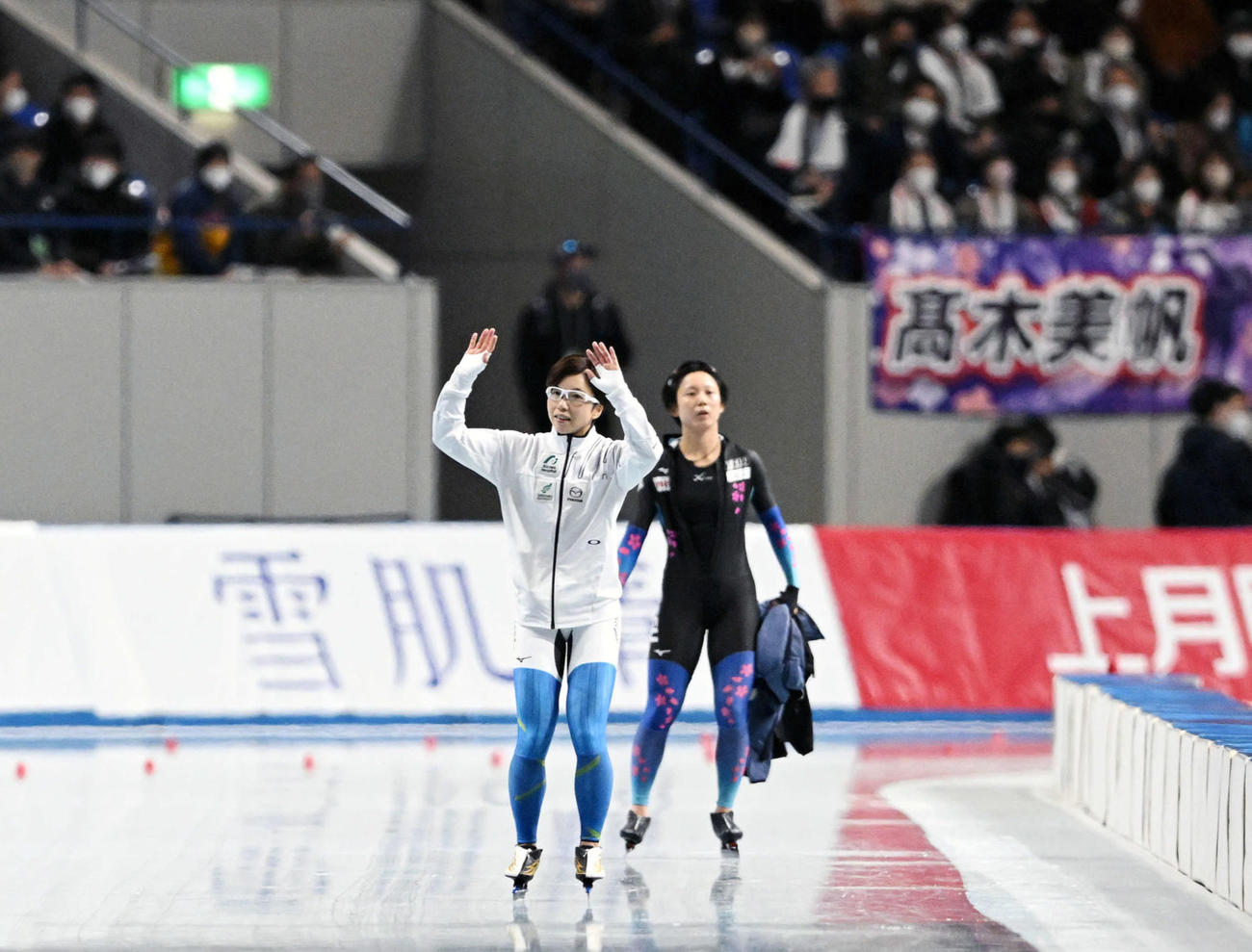 引退レースを終えた小平（左）は会場のファンに手を振る。右は高木美帆（撮影・滝沢徹郎）