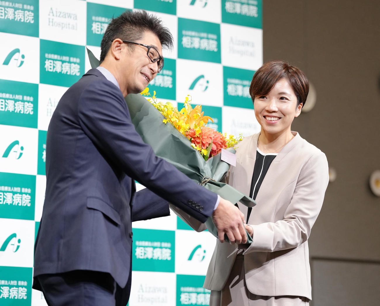 引退会見で結城コーチ（左）から花束を贈られ笑顔を見せる小平さん（撮影・垰建太）