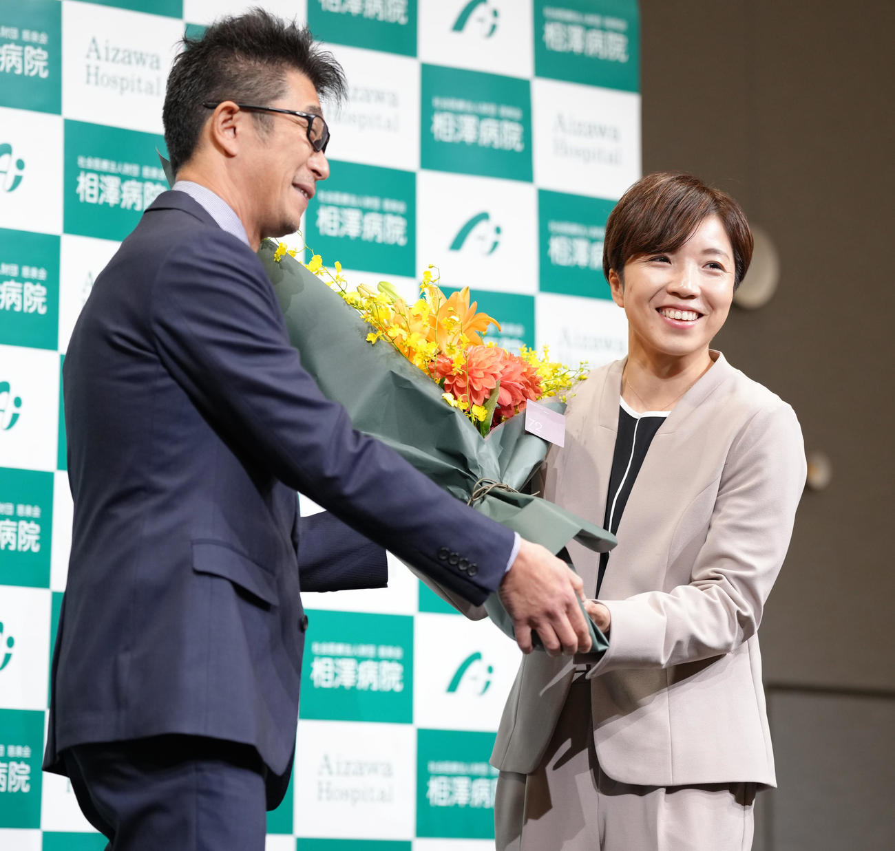 引退会見で結城コーチ（左）から花束を贈られ笑顔を見せる小平さん（撮影・垰建太）