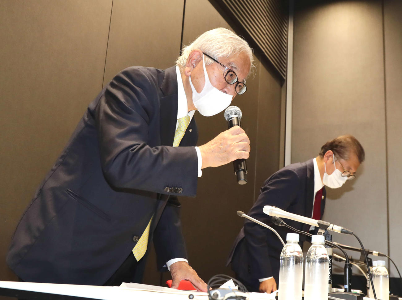 21日、会見で頭を下げるバドミントン協会の関根会長（左）