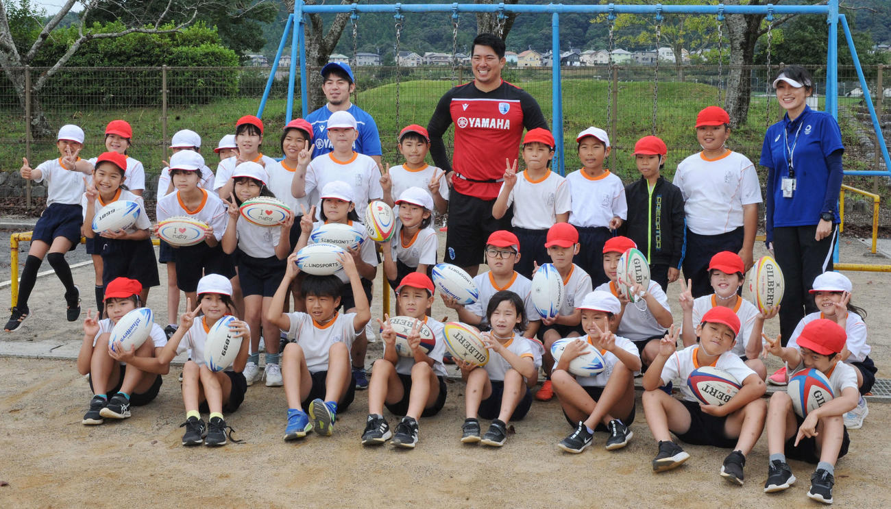 静岡ブルーレヴズの選手2人と記念撮影に納まる島田大津小4年の児童たち