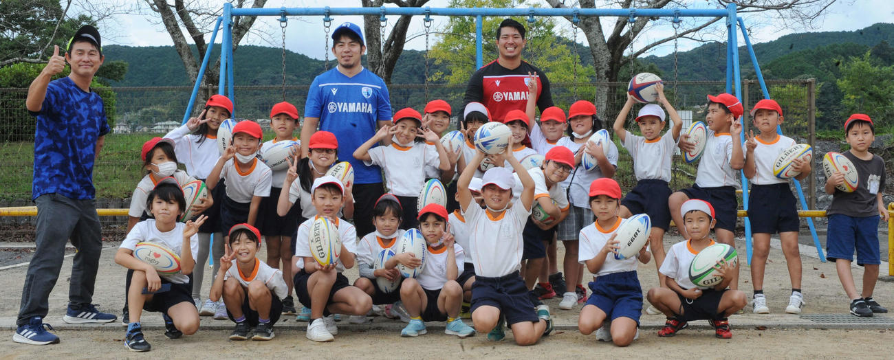 静岡ブルーレヴズの選手2人と記念撮影に納まる島田大津小3年の児童たち