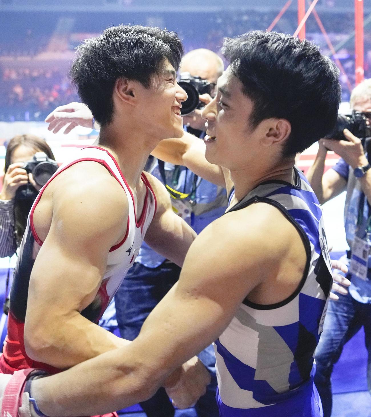 男子個人総合で初優勝し、3位の谷川航（右）と喜ぶ橋本大輝＝リバプール（共同）