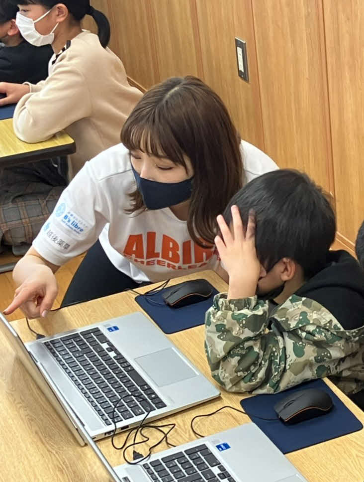 小学生と一緒にパソコンでキャラクター作りをするアルビチアの小野寺（アルビレックスチアリーダーズ提供）