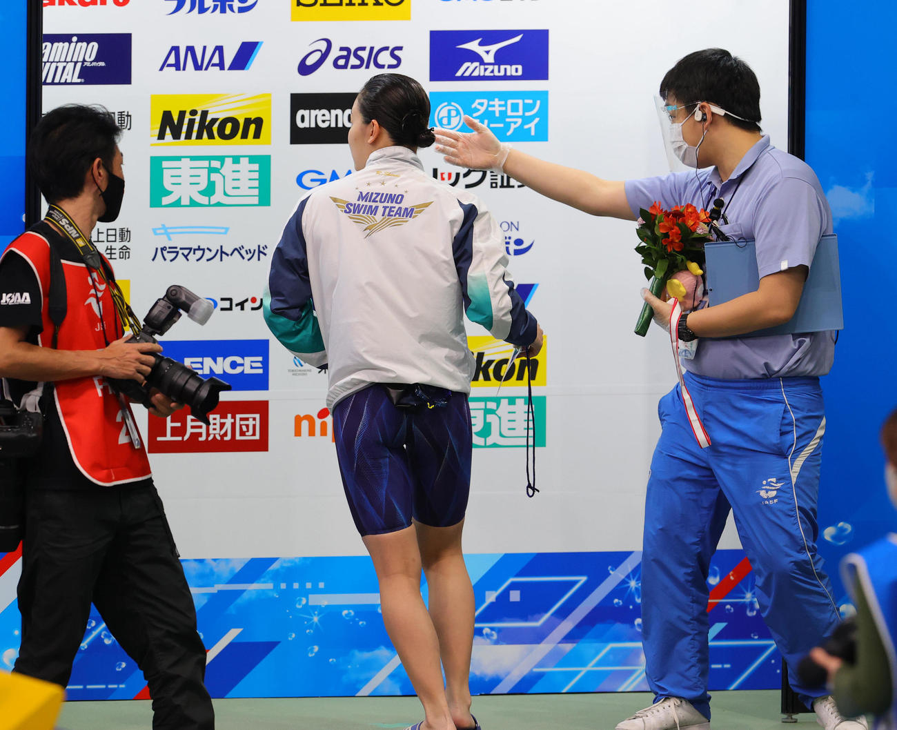 女子200メートル自由形で優勝した白井は表彰を終わると、金メダルと花束を関係者に預け次の女子100メートル背泳ぎ決勝の招集所に走って向かう（撮影・野上伸悟）