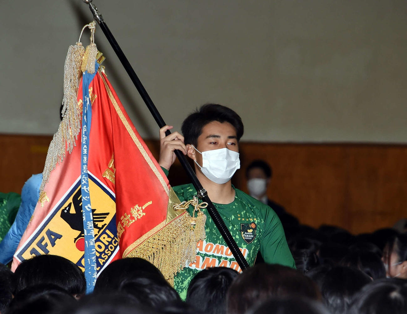 壮行式で優勝旗を持って入場する青森山田サッカー部・多久島主将
