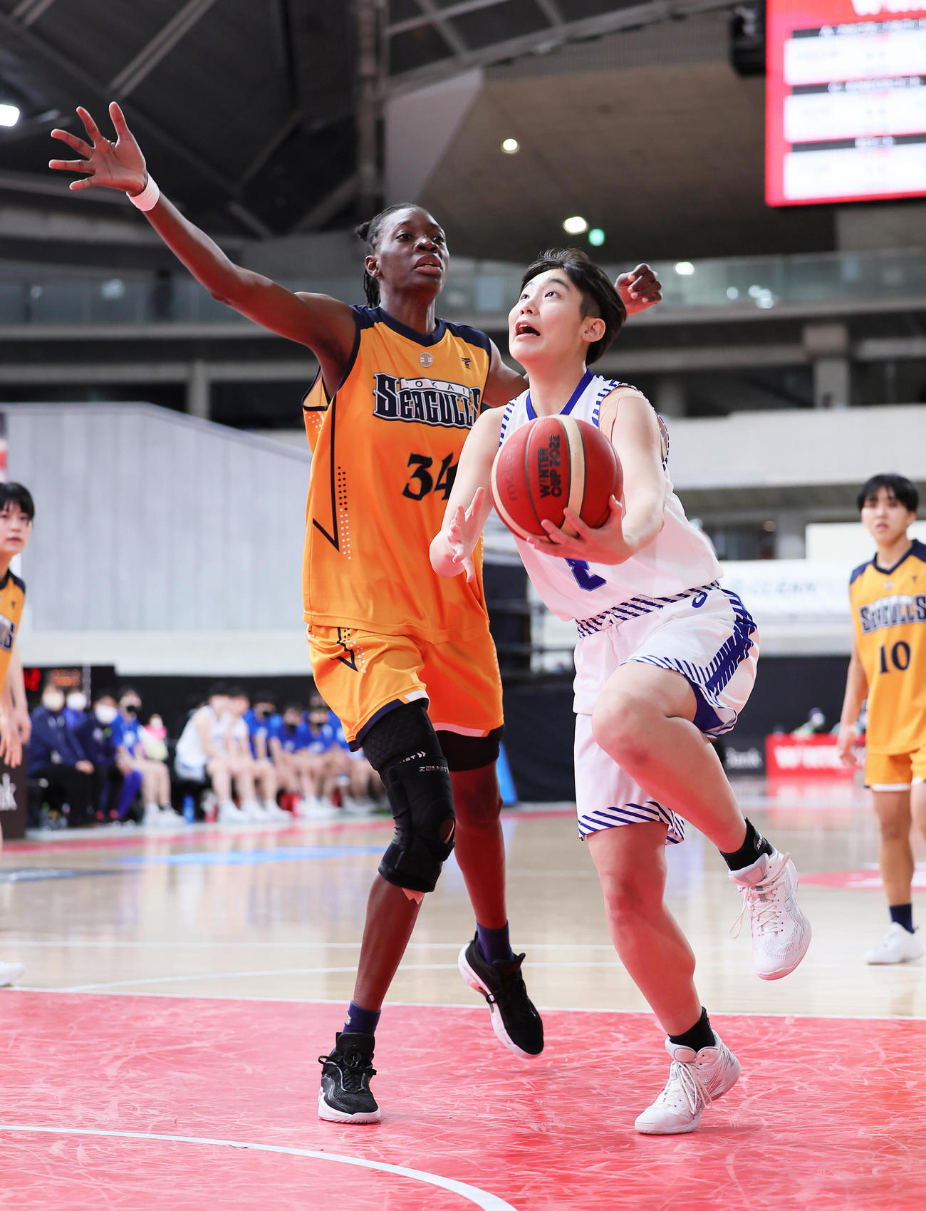 聖和学園対東海大福岡　第1Q、東海大福岡・ファール・アミナタ（左）のブロックを受けながらシュートを放つ聖和学園・横山（撮影・足立雅史）