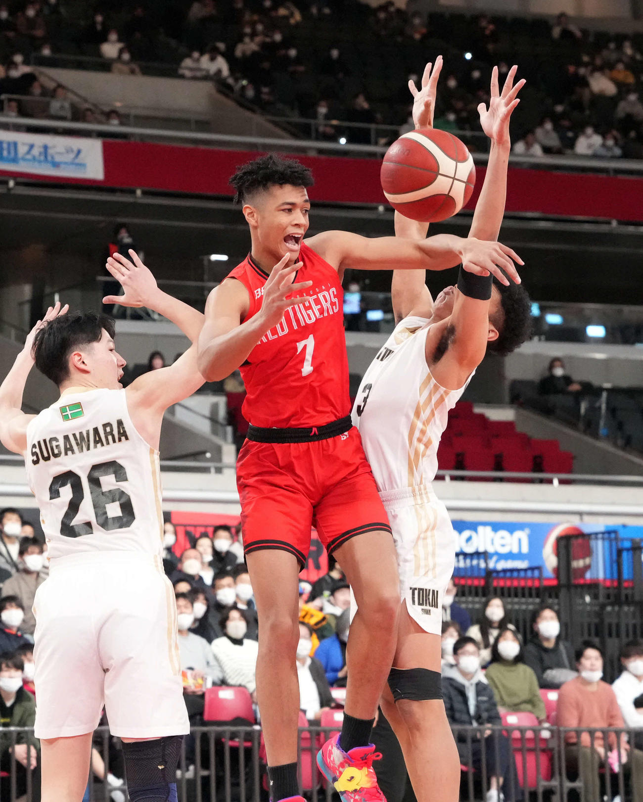 第1Q、相手に囲まれながら、パスを出す開志国際・介川（中央）（撮影・狩俣裕三）