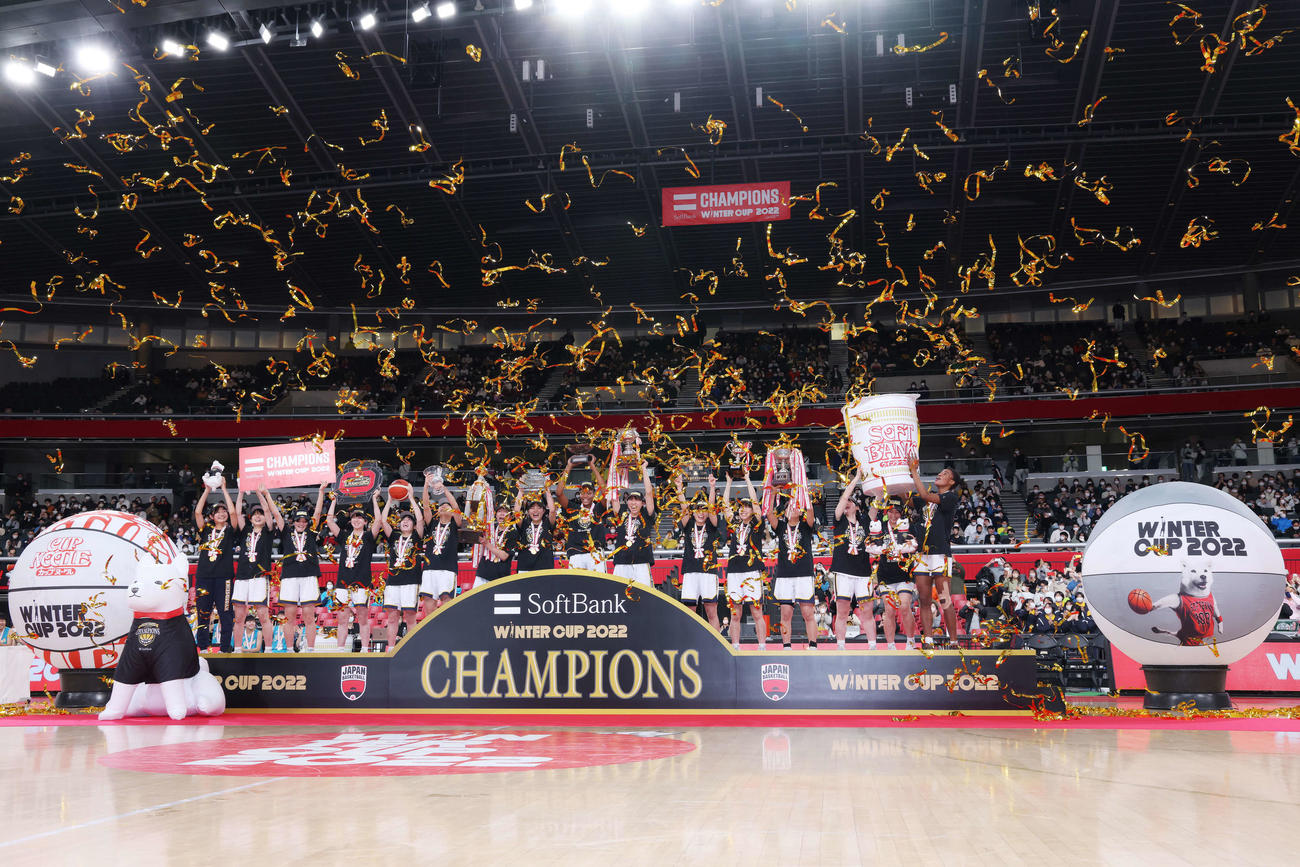 女子優勝を決め、降り注ぐテープシャワーの中でトロフィーを掲げながら写真に納まる京都精華学園の選手たち（撮影・河田真司）