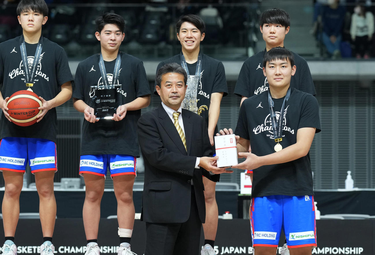 全国U15バスケットボール選手権大会で優勝したライジングゼファーフクオカU15に記念品を贈る篠田ビジネス開発部次長（前列左）（撮影・菅敏）