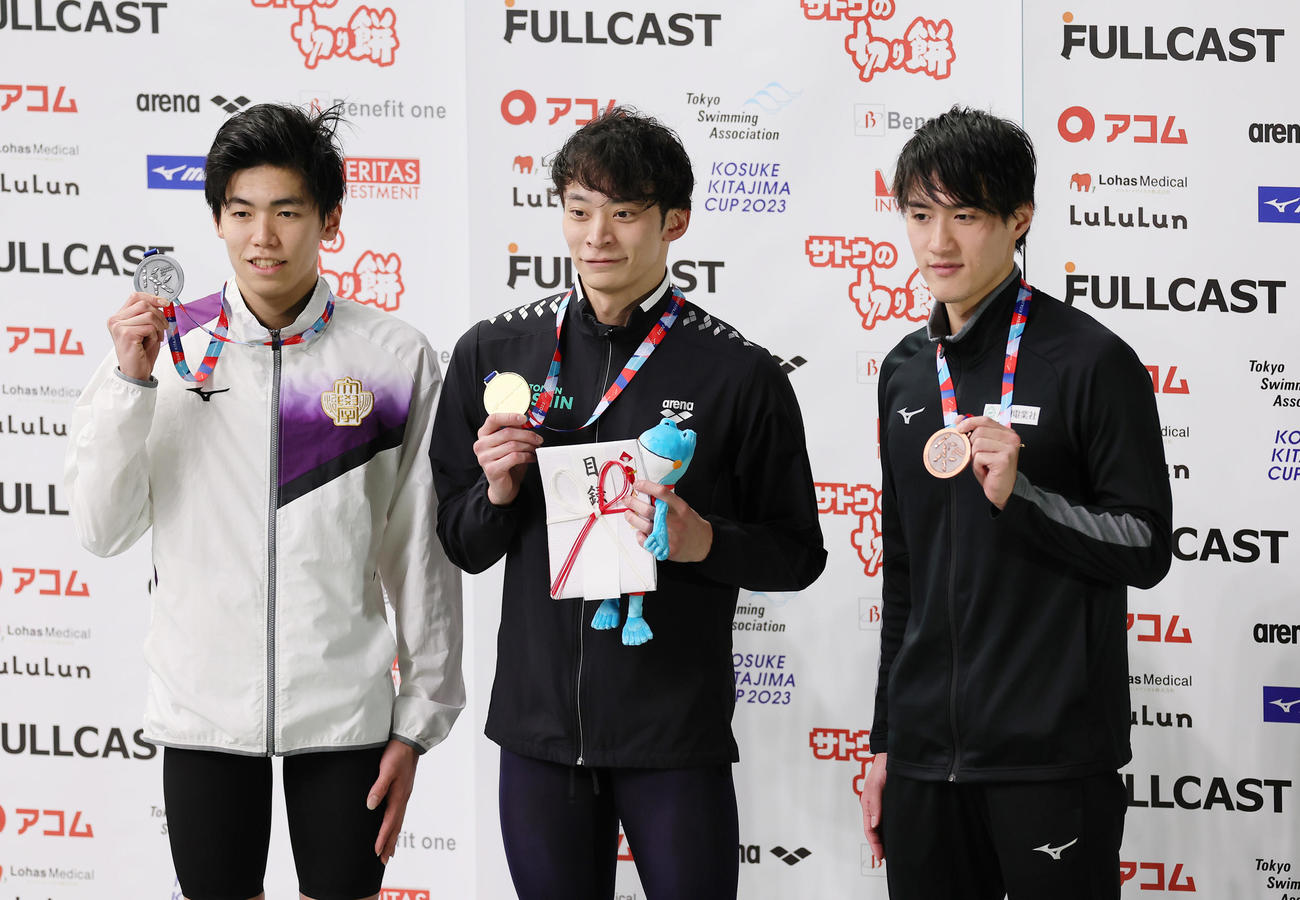 男子100メートル背泳ぎで優勝し表彰式で笑顔を見せる入江（中央）。左は2位松山、右は3位内藤（撮影・足立雅史）