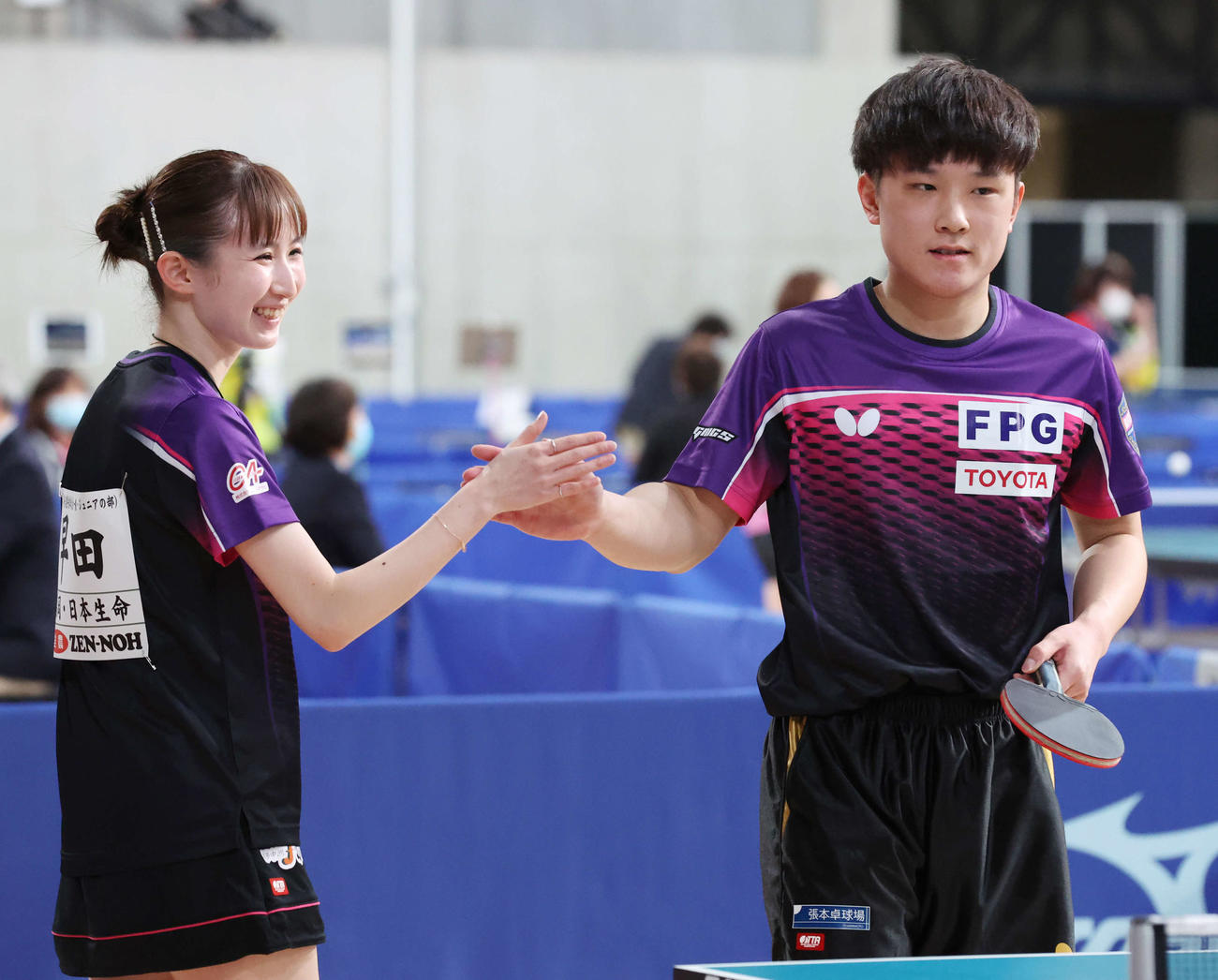 混合ダブルス準々決勝を勝利し、笑顔でタッチする早田（左）と張本智（撮影・宮地輝）