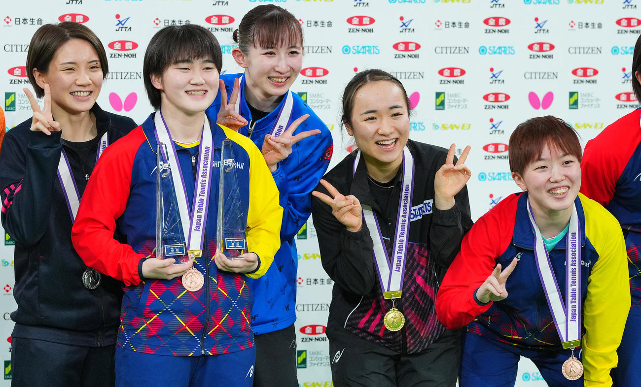 表彰式でなぜか優勝トロフィーを大藤（左から2人目）に持たせ笑顔を見せる伊藤（同4人目）、早田（同3人目）（撮影・垰建太）
