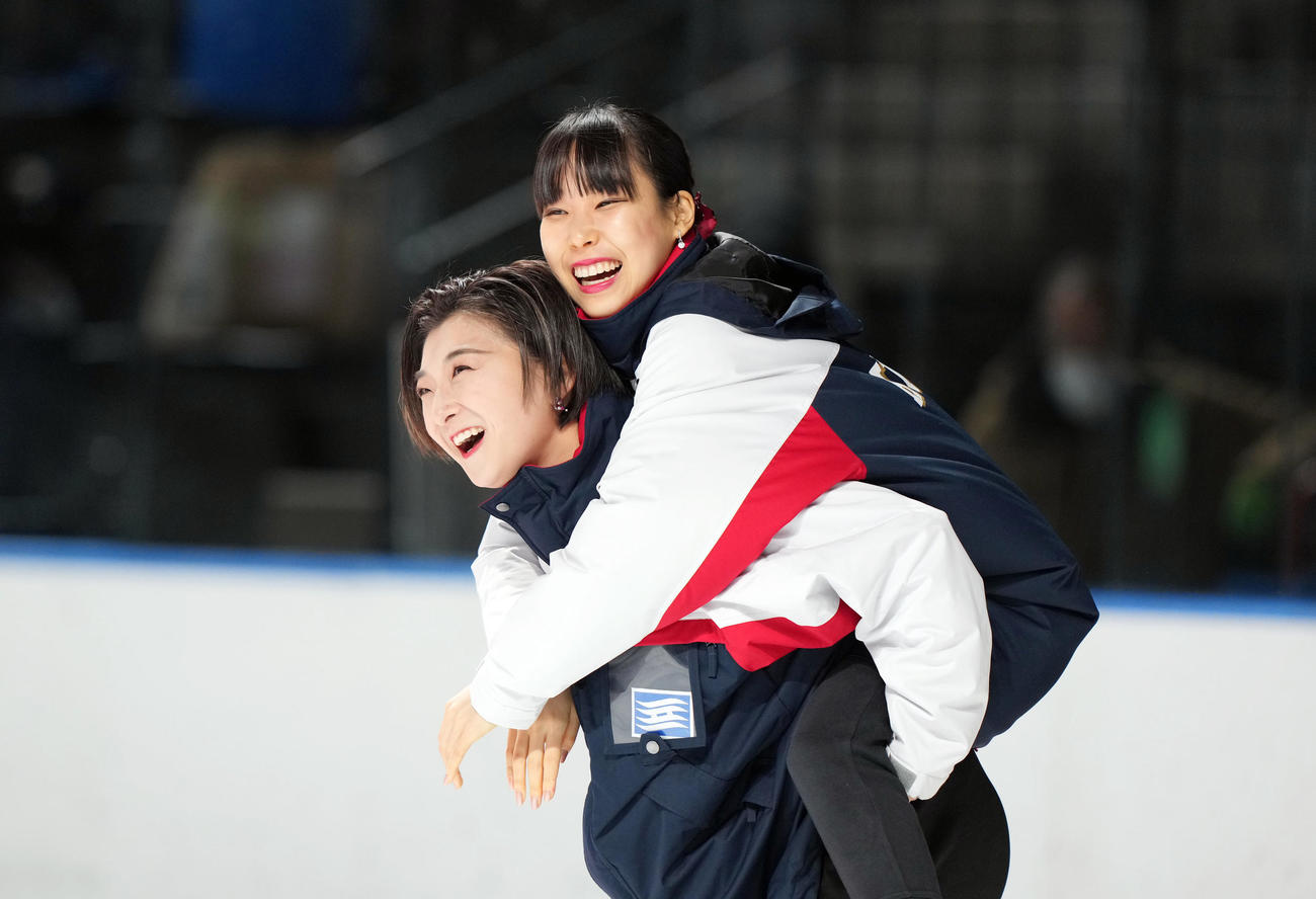 成年女子フィギュアスケートの表彰式で団体、個人ともに優勝し、チームメートの三原（右）をおんぶしながら登場する坂本（兵庫）（撮影・狩俣裕三）