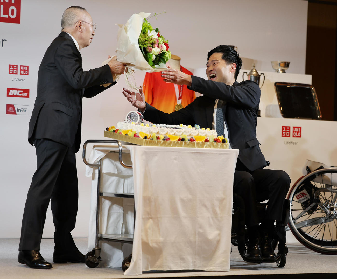 引退会見でユニクロ柳井会長兼社長（左）から花束を受け取る国枝。サプライズのお祝いケーキも贈られた（撮影・野上伸悟）