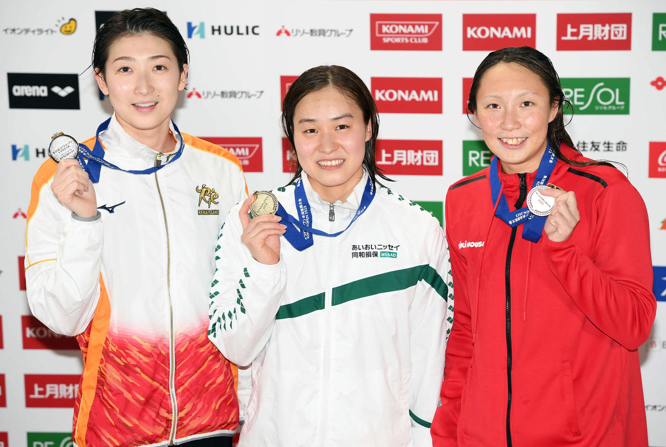 女子100メートルバタフライ決勝　2位となり表彰式で笑顔を見せる池江（左）。中央は優勝した牧野、右は3位の相馬（撮影・たえ見朱実）