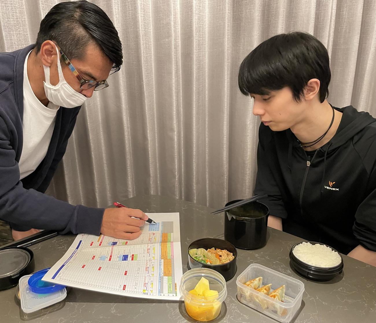 味の素VPの栗原秀文チームリーダー（左）から「プロローグ」横浜公演の食サポートに関して説明を受ける羽生さん