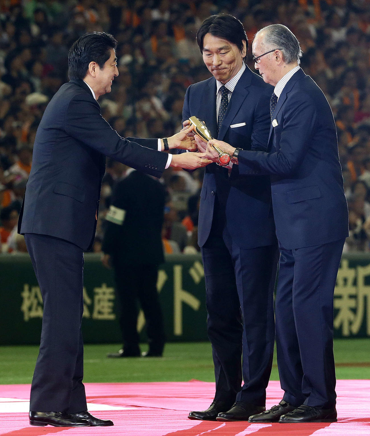 国民栄誉賞の記念品である金のバットを松井氏（中央）の手を借り安倍首相（左）から受け取る長嶋氏（2013年5月5日撮影）