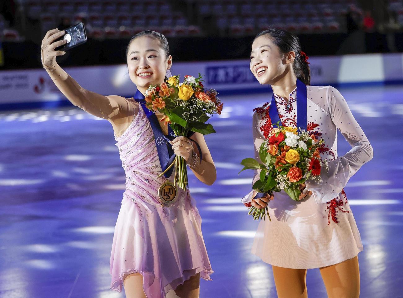 世界ジュニア選手権で日本勢史上最年少優勝した島田麻央（左）は、銅メダルの中井亜美と仲良く自撮り（ISU提供・ゲッティ＝共同）